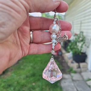 May include: A pink crystal teardrop dangle earring with a silver chain and white pearl beads.