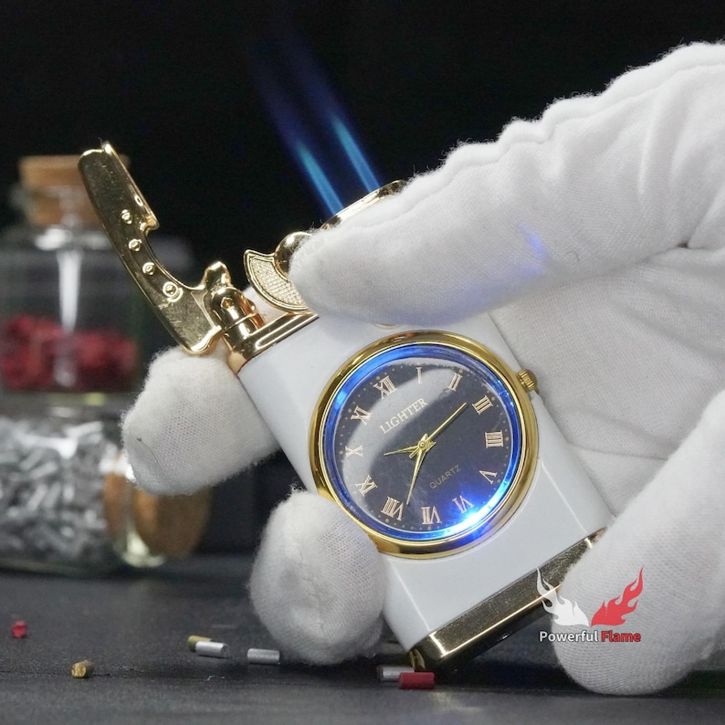 May include: White lighter with a gold trim and a clock face that reads "LIGHTER QUARTZ". The lighter is being lit with a blue flame.