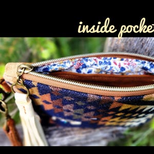 Puede incluir: Bolsa con cremallera abierta con un colorido estampado geom&eacute;trico en azul, naranja y marr&oacute;n. El forro interior presenta un estampado floral. Una borla color crema cuelga del lateral. El texto "inside pocket" es visible.