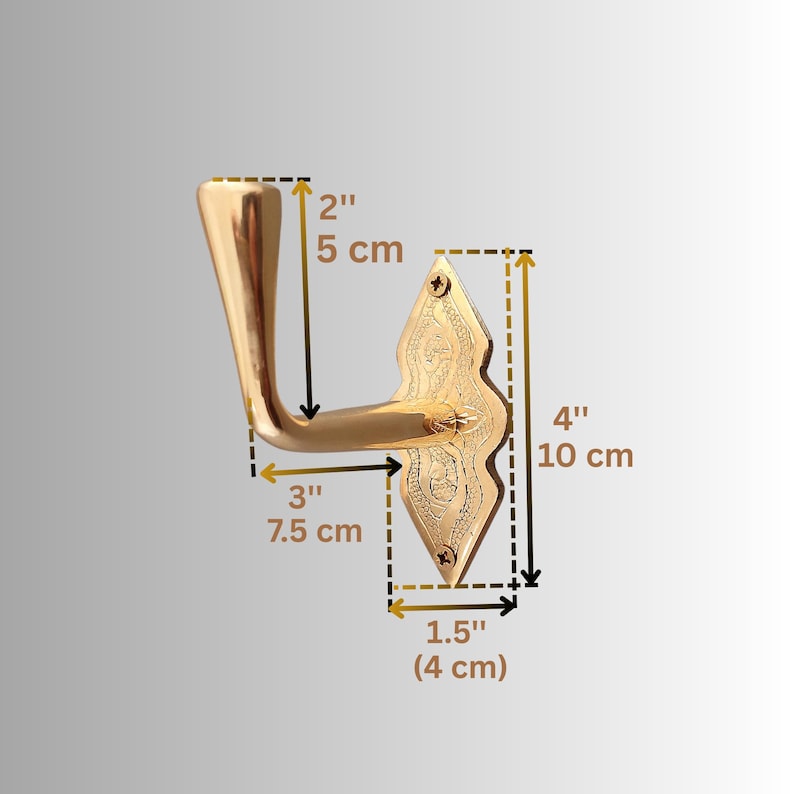 May include: A gold-coloured door handle with an ornate, diamond-shaped backplate. The handle is 7.5 cm long, and the backplate is 10 cm tall and 4 cm wide. The handle is 5 cm from the top to the bend.