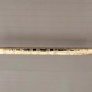 K&ouml;nnte beinhalten: Eine goldfarbene Metall-Handtuchhalterung mit einem verzierten Design. Die Stange hat abgerundete Enden und ist an einer Wand montiert.
