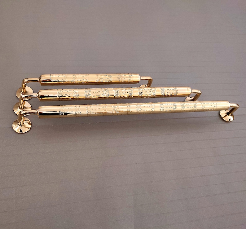 K&ouml;nnte beinhalten: Vier goldfarbene T&uuml;rklinken aus Metall mit einem verzierten Design. Die Griffe sind in einer Reihe angeordnet, wobei der l&auml;ngste Griff unten und der k&uuml;rzeste Griff oben ist.