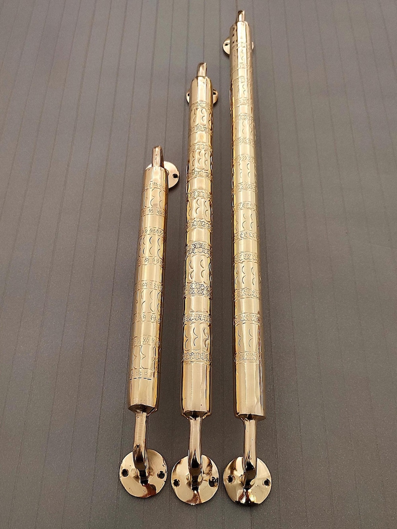 K&ouml;nnte beinhalten: Drei goldfarbene T&uuml;rklinken mit einem verzierten Design. Die Griffe sind unterschiedlich gro&szlig; und sind der Gr&ouml;&szlig;e nach von links nach rechts angeordnet.