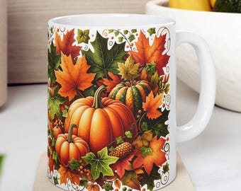May include: White ceramic mug featuring a vibrant autumn design. The mug showcases a collection of pumpkins, fall leaves in shades of orange, red, and green, and decorative vines. The mug is placed on a square coaster.