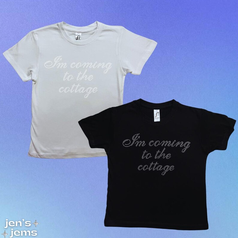 May include: Two short-sleeved t-shirts, one white and one black, are displayed. Each shirt features the text "I'm coming to the cottage" in a cursive font. The shirts are on a gradient blue background. The brand name "jen's + jems" is in the bottom left corner.