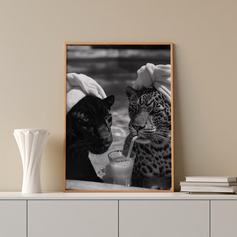 May include: Black and white photo of two animals, a black panther and a jaguar, wearing towels on their heads, sitting side by side and drinking from a glass with a straw.