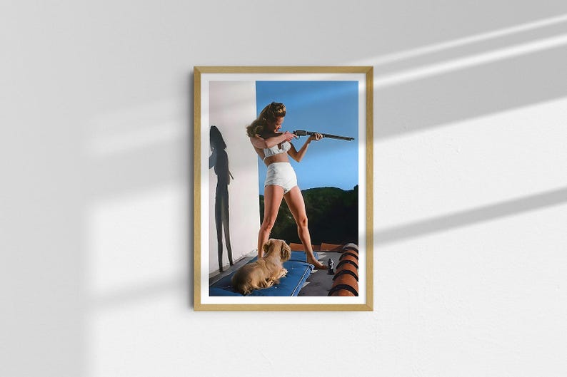 May include: A woman in a white swimsuit holds a rifle and aims it towards the right side of the frame. She is standing on a rooftop with a small dog lying at her feet. The background is a blue sky with some trees in the distance.