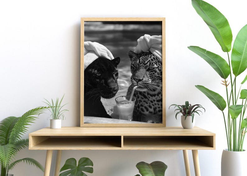 May include: Black and white photo of two leopards wearing white towels on their heads, sitting side by side and drinking from straws out of glasses.