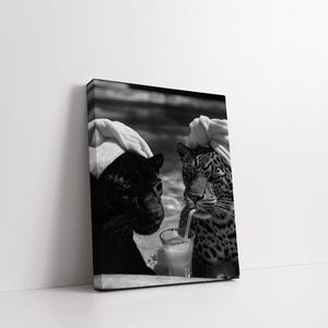 May include: Black and white photo of two large cats, a black panther and a leopard, wearing white towels on their heads. The leopard is drinking from a glass with a straw.
