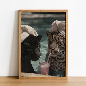 Peut inclure: Impression encadr&eacute;e d'une panth&egrave;re noire et d'un l&eacute;opard, semblant &ecirc;tre dans une piscine. Le l&eacute;opard boit une boisson rose avec une paille. L'impression est dans un cadre en bois et sur fond blanc.