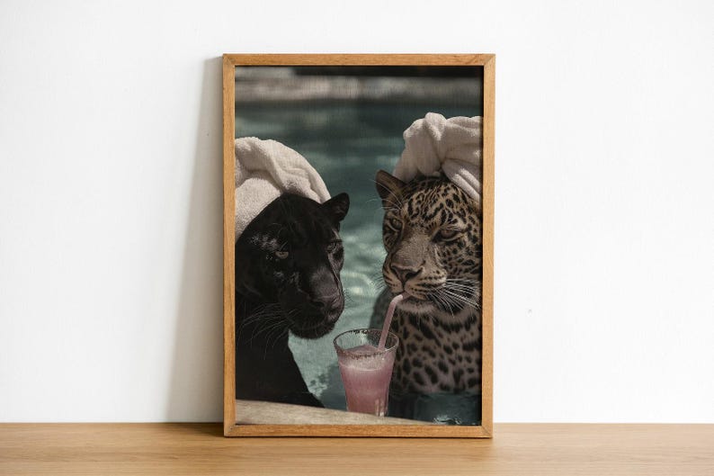Peut inclure: Impression encadr&eacute;e d'une panth&egrave;re noire et d'un l&eacute;opard, semblant &ecirc;tre dans une piscine. Le l&eacute;opard boit une boisson rose avec une paille. L'impression est dans un cadre en bois et sur fond blanc.