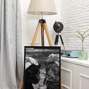 May include: Black and white photo of a black panther and a leopard drinking a cocktail together. The photo is framed in a black frame.