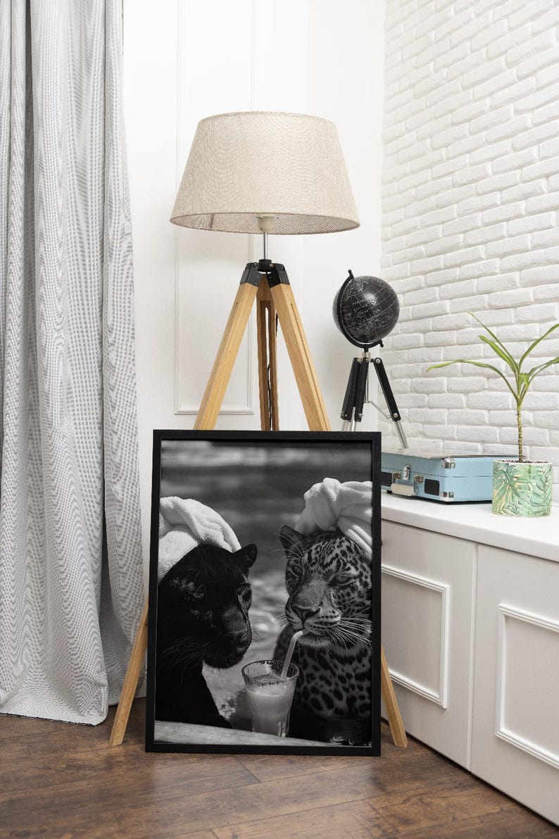 May include: Black and white photo of a black panther and a leopard drinking a cocktail together. The photo is framed in a black frame.
