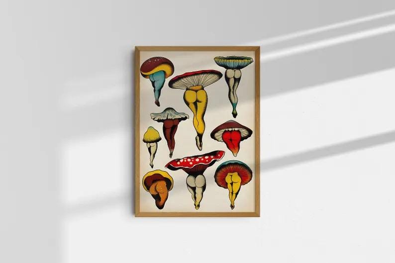 May include: A framed art print featuring whimsical illustrations of mushrooms with human-like legs. The mushrooms have various cap colors, including red, yellow, and blue, and are set against a cream-colored background.