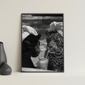 May include: Black and white photo of two leopards wearing white towels on their heads, one is drinking from a glass with a straw.
