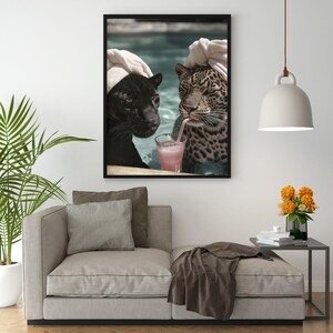 Peut inclure: Une impression d'art encadr&eacute;e montre une panth&egrave;re noire et un l&eacute;opard se relaxant dans une piscine, chacun portant une serviette sur la t&ecirc;te. Le l&eacute;opard boit une boisson rose avec une paille. L'&oelig;uvre est affich&eacute;e au-dessus d'un canap&eacute; beige.
