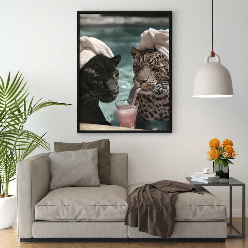 Peut inclure: Une impression d'art encadr&eacute;e montre une panth&egrave;re noire et un l&eacute;opard se relaxant dans une piscine, chacun portant une serviette sur la t&ecirc;te. Le l&eacute;opard boit une boisson rose avec une paille. L'&oelig;uvre est affich&eacute;e au-dessus d'un canap&eacute; beige.