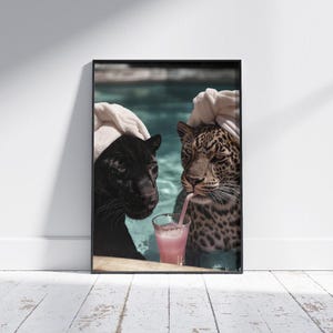 Peut inclure: Impression artistique encadr&eacute;e repr&eacute;sentant une panth&egrave;re noire et un l&eacute;opard dans une piscine, chacun portant une serviette blanche sur la t&ecirc;te. Le l&eacute;opard boit une boisson rose avec une paille. Th&egrave;me humoristique et d&eacute;tendu.