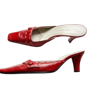 May include: Red leather slip-on heels with a square toe and a small buckle detail. The heels have a stiletto heel and white stitching accents. The brand name "BANDOLINO" is visible on the insole.