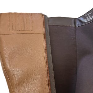 Puede incluir: Primer plano de una bota de cuero marr&oacute;n claro con cremallera. La bota tiene una superficie texturizada y un forro interior marr&oacute;n. La cremallera es de color marr&oacute;n oscuro. La parte superior de la bota tiene costuras decorativas.