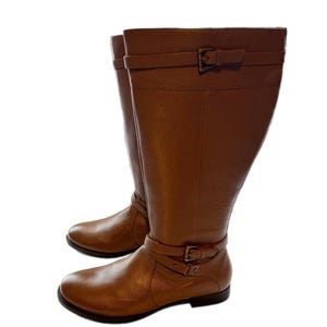 Puede incluir: Un par de botas altas de cuero marr&oacute;n. Cada bota tiene una correa con hebilla alrededor del tobillo y otra en la parte superior. Las botas tienen punta redonda y tac&oacute;n bajo.