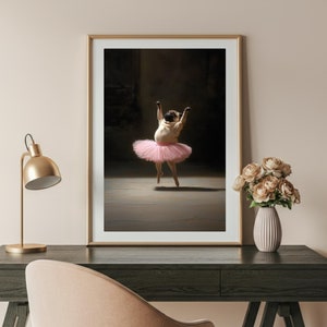 May include: A framed photograph of a pug wearing a pink tutu and dancing on a stage. The photo is in a gold frame and is hanging on a wall.