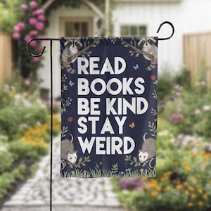 May include: A navy blue garden flag with the words "READ BOOKS BE KIND STAY WEIRD" in white. The flag features illustrations of raccoons, opossums, butterflies, ladybugs, and foliage.