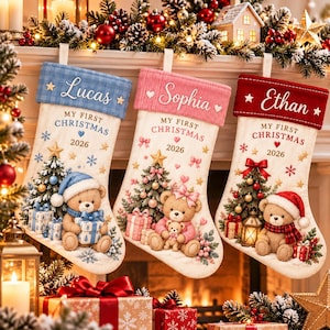 May include: Three personalized Christmas stockings featuring teddy bears, Christmas trees, and gifts. The blue cuff reads Lucas, the pink cuff reads Sophia, and the red cuff reads Ethan. Each stocking displays the text My First Christmas 2026.