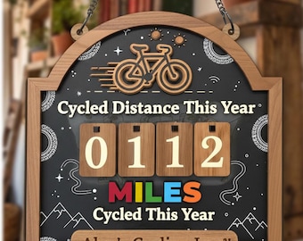 May include: Wooden cycling log with a chalkboard background. The sign reads "Cycled Distance This Year" and displays "0112 MILES Cycled This Year." A bicycle graphic and the text "Alex's Cycling Log" are also featured.
