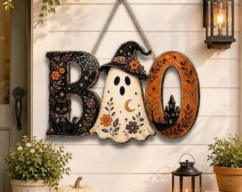 May include: A decorative hanging sign spelling BOO, featuring a black letter B with a cat, a ghost wearing a witch hat as the letter O, and an orange letter O with a haunted house silhouette. The sign is suspended by a rope from a wall hook.