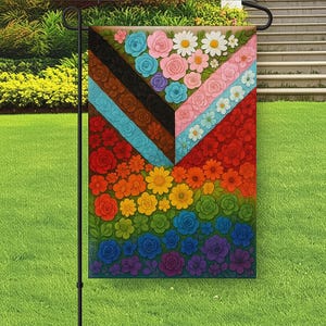 以下が含まれることがあります： カラフルなガーデンフラッグ。花柄のデザインで、バラやデイジーなど、虹色の花が幾何学模様に配置されています。黒い金属製のスタンドに立てられ、芝生の庭に飾られています。