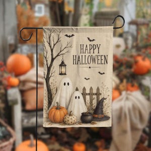 May include: A rectangular garden flag with a beige background featuring the text HAPPY HALLOWEEN. The design includes two white ghosts, a large orange pumpkin, a small white pumpkin, a black witch hat, a cauldron, a lantern, and bats.