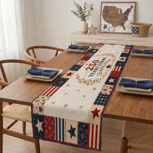May include: A patriotic table runner with a cream-colored center and patterned borders in red, white, and blue. The runner features stars, stripes, and the text "250 Years Strong Since 1776". It is placed on a wooden table with place settings.