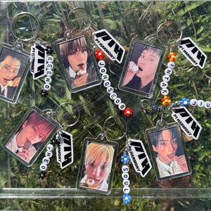 Puede incluir: Siete llaveros de plástico transparente con texto en blanco y negro que dice "P1Harmony" y los nombres de cada miembro del grupo: "Keeho", "Theo", "Soul", "Jongseob", "Intak", "Jiung". Cada llavero tiene la foto de un miembro diferente en un marco de plástico transparente.