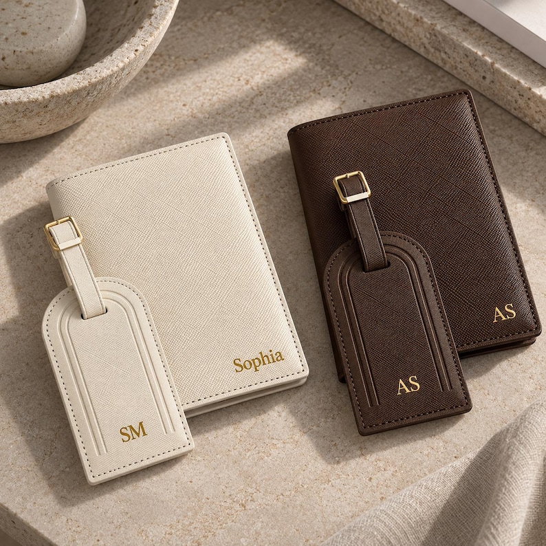 May include: A cream passport holder with the name Sophia and a matching luggage tag with the initials SM, alongside a dark brown passport holder with the initials AS and a matching luggage tag with the initials AS, all featuring gold text.