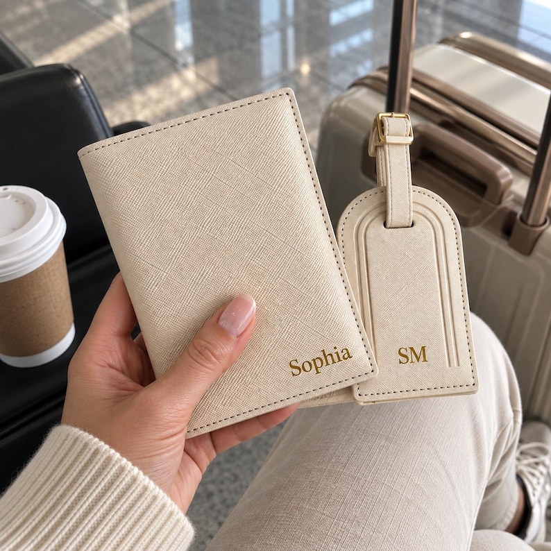 May include: A cream-colored passport holder with the name Sophia embossed in gold and a matching luggage tag with the initials SM embossed in gold. Both items feature a textured finish and are made of a durable, synthetic material.