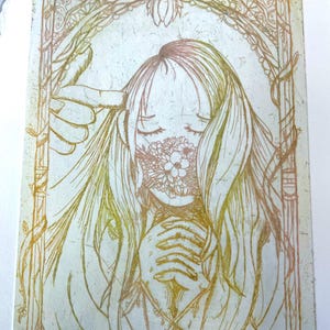 May include: A line drawing of a person with long hair wearing a mask made of flowers. The drawing is in shades of gold and pink and is framed with a decorative border.