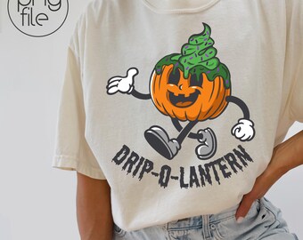 May include: Cream-colored t-shirt featuring a cartoon pumpkin character with a green topping. The pumpkin has a smiling face and is walking, with the text "DRIP-O-LANTERN" below. The design is in orange, green, black, and white.