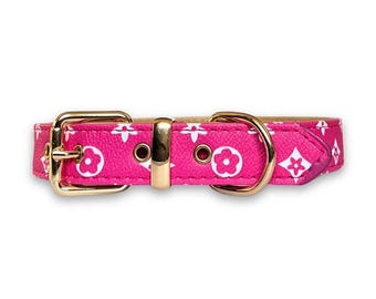 Peut inclure: Un collier pour chien rose avec un motif blanc et or. Le collier a une boucle dorée et un anneau en D doré.