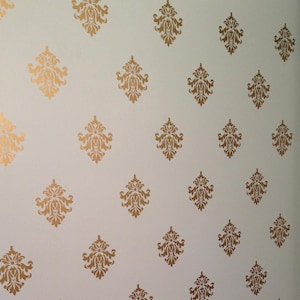 May include: A light blue wall with a repeating pattern of gold damask decals. The decals are arranged in a diamond pattern.