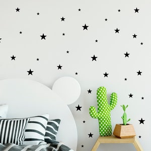 May include: A white bed with a black and white striped comforter and pillows. The headboard is shaped like a bear's head. The wall behind the bed is white with black star stickers. A green cactus and a small plant are on a wooden side table.