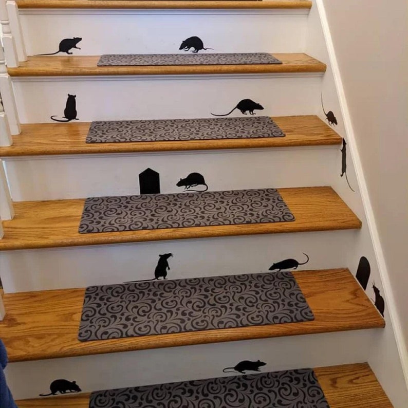 May include: A set of black rat silhouette decals on a white staircase with brown wooden steps and grey patterned stair treads. The decals are arranged in a playful pattern, creating a whimsical and spooky Halloween decor.
