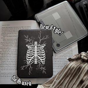 May include: A black e-reader case featuring a white line art illustration of a human rib cage with branches and leaves. The text New style! and No Ai used is visible. The case is placed on an open book next to a clear protective cover.
