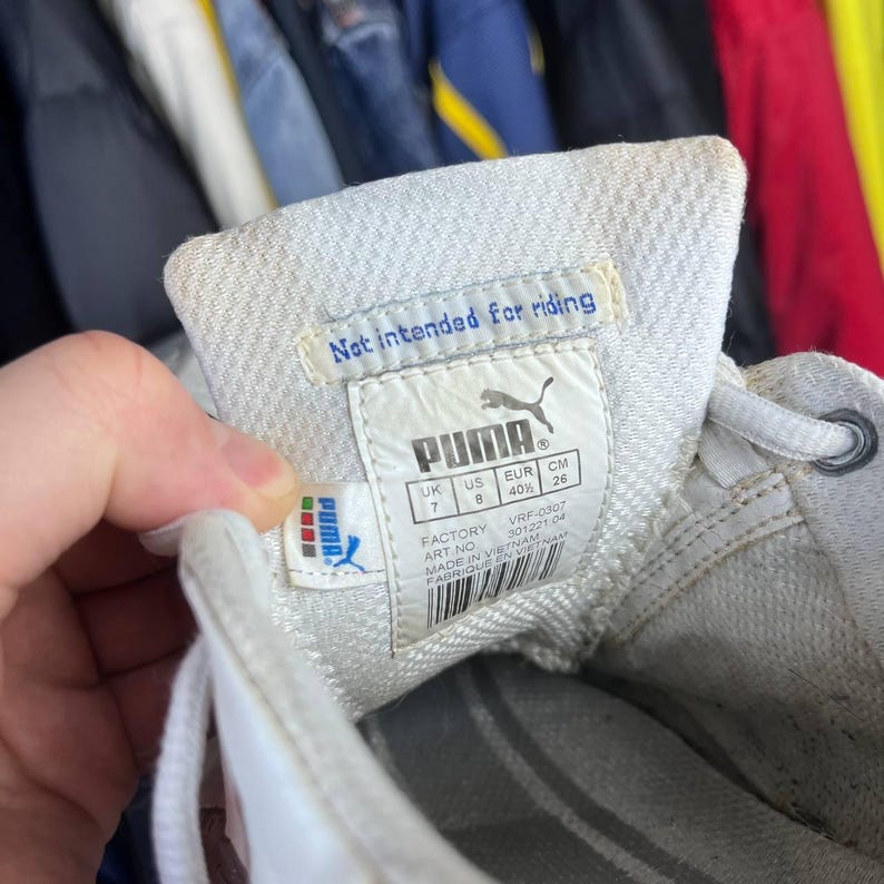 May include: Close-up of a white Puma sneaker's interior, showcasing the brand label with the Puma logo and text that reads "Not intended for riding." The label also includes size information: UK 7, US 8, EUR 40%, and CM 26.
