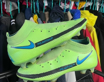 May include: Pair of neon green soccer cleats with black accents and a blue swoosh logo. The cleats have a sock-like collar and the word "PHANTOM" is printed on the side.