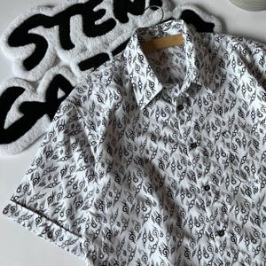 May include: White short-sleeved button-down shirt with a black and white pattern of stylised flames.