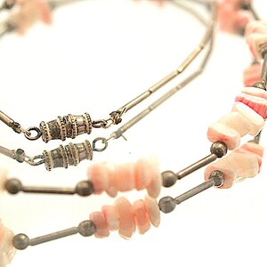 Puede incluir: Un collar de doble cadena con cuentas de concha rosa y blanca y separadores plateados. El collar tiene dos cierres de barril plateados.