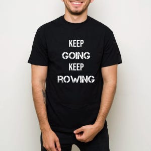 May include: Black crew neck t-shirt with the words "KEEP GOING KEEP ROWING" printed in white. The text is stacked vertically, with each word centered. The shirt is made of a soft material.