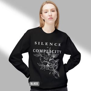 May include: Black sweatshirt with a white floral design and the text "Silence is Complicity".