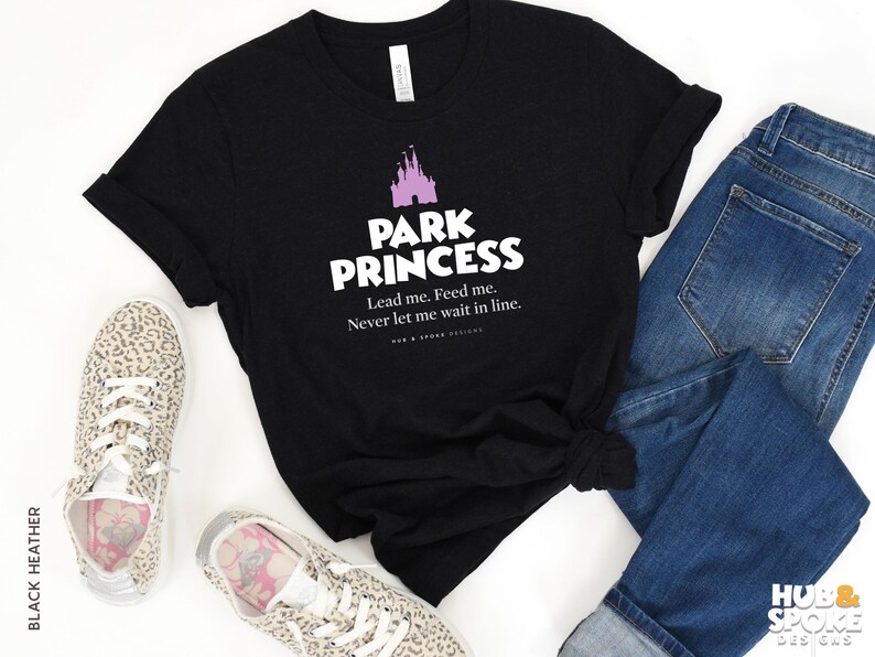 Może przedstawiać: Czarny T-shirt z grafiką r&oacute;żowego zamku i tekstem "Park Princess. Lead me. Feed me. Never let me wait in line."